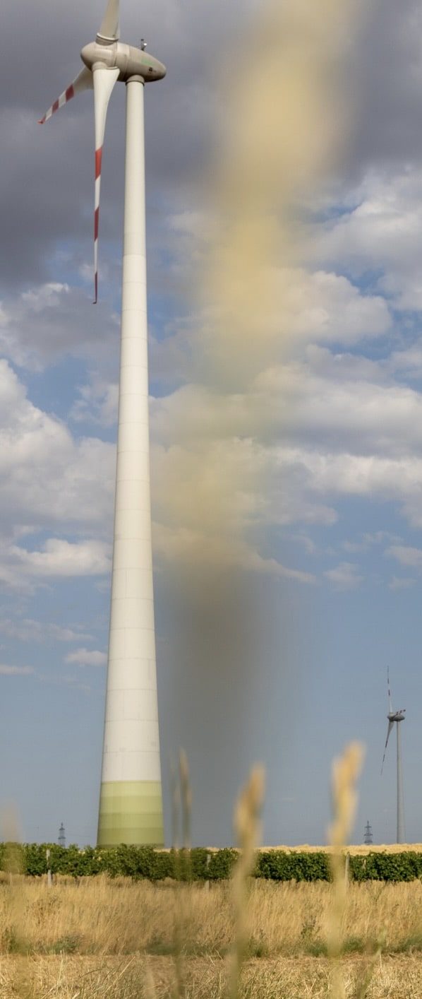 Windkraftanlage vor weißem Wolkenhorizont mit einem Regenbogen