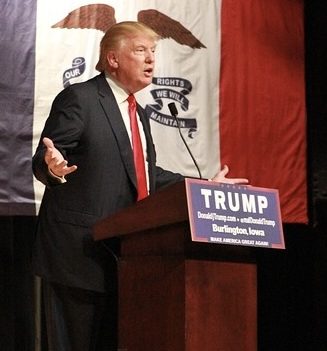 Donald Trump Trump im dunkelblauen Anzug mit ausgebreiteten Armen am Rednerpult