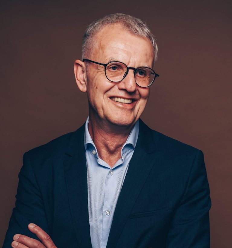 Detlef Flintz Porträtbild, ca. 60jähriger Mann mit Brille in blauem Anzug